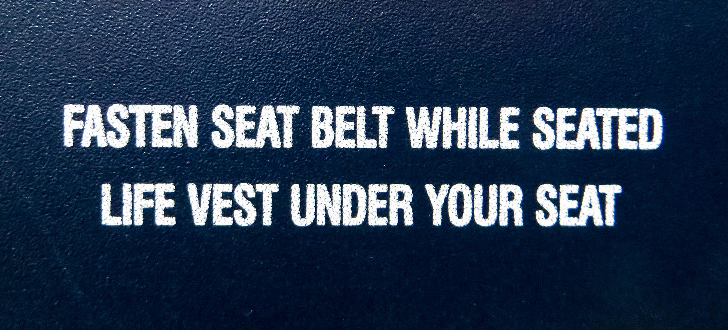 POV shot of an anxious worried person who is scared of flying reading a safety sign about fastening their seat belt while they are on a flight.