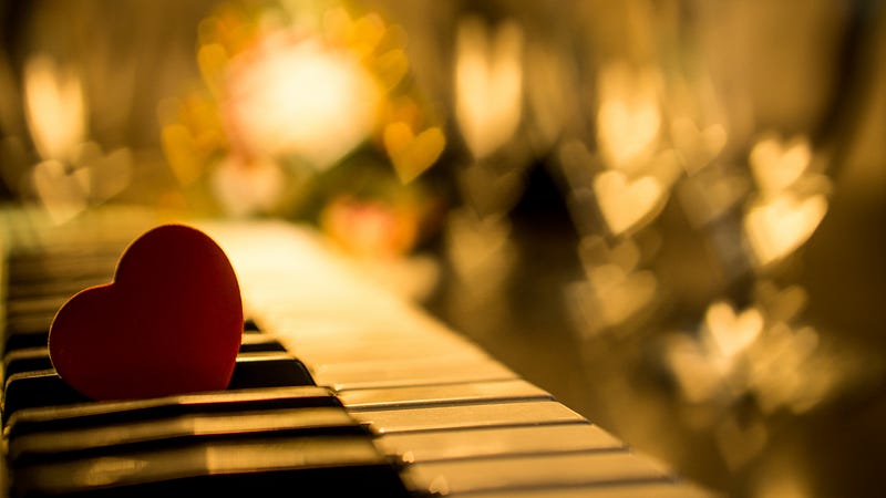A picture of a cut-out heart wedged between keys on a piano with blurred illuminated hearts in the background A picture of a cut-out heart wedged between keys on a piano with blurred illuminated hearts in the background