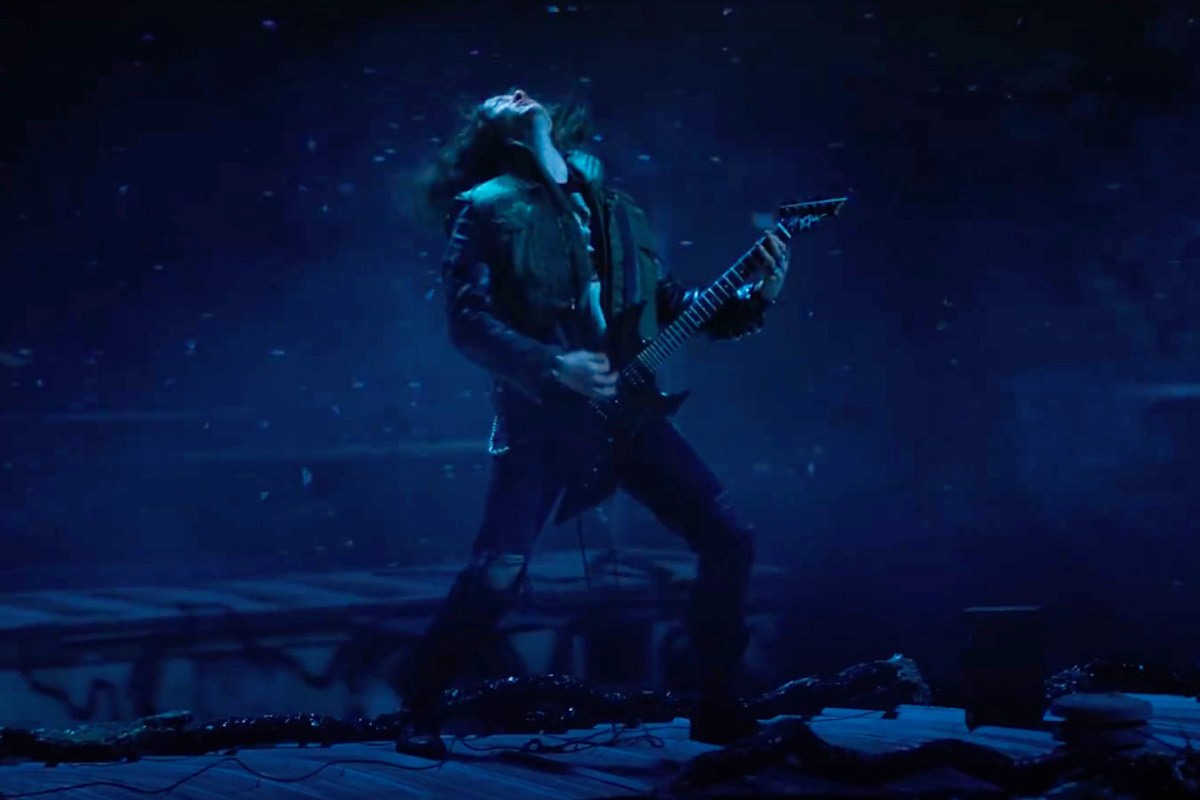 A long-haired Eddie Munson is playing electric guitar in a scene from Stranger Things