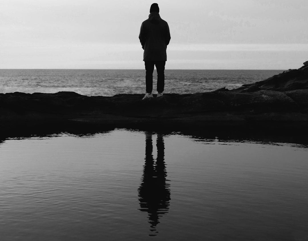 person standing in front of sea person standing in front of sea