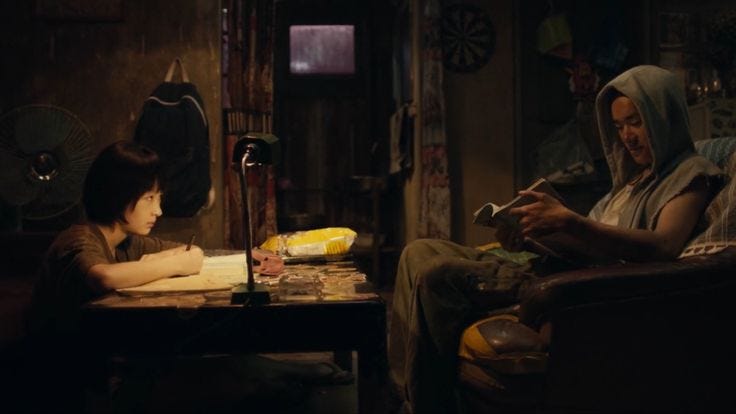 This may contain: a woman sitting in a chair next to a man who is writing on a piece of paper