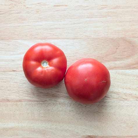 Three types of tomatoes used for tomato tuna—Roma tomatoes, heirloom tomatoes, and classic red slicer tomatoes displayed on a cutting board.