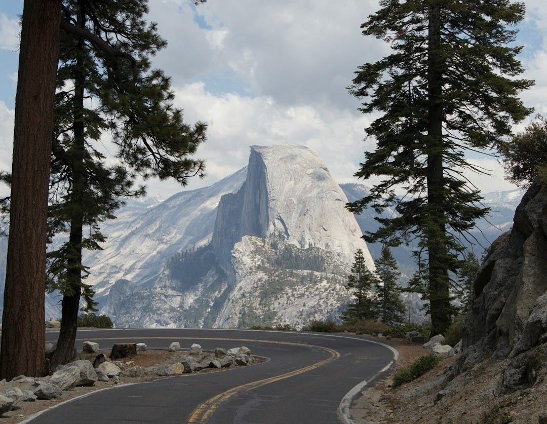 snow covered mountain in front of road during daytime