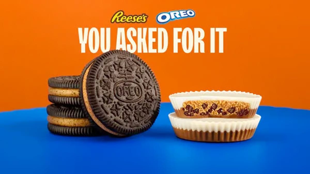 A stack of Oreos with orange filling next to a stack of white and orange Reese's cups with tiny cookie bits in the peanut butter in the middle. The top has both logos and says "You asked for it"