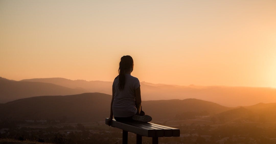 woman sitting on bench over viewing mountain