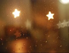 This may contain: stars are seen through the rain on a window