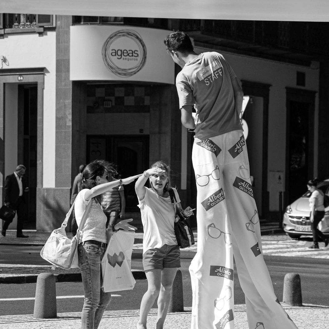 grayscale photo of man in white shirt and pants standing on sidewalk