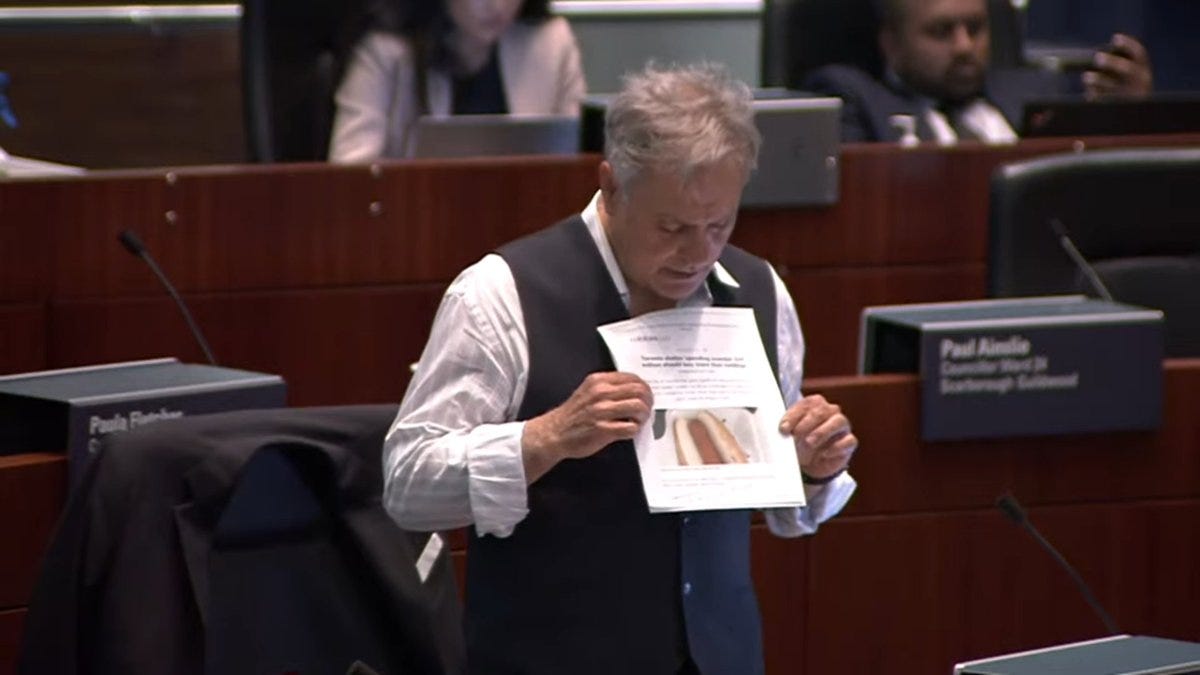 A photo of Councillor Anthony Perruzza holding up a photo of a hot dog at the June meeting of Council A photo of Councillor Anthony Perruzza holding up a photo of a hot dog at the June meeting of Council