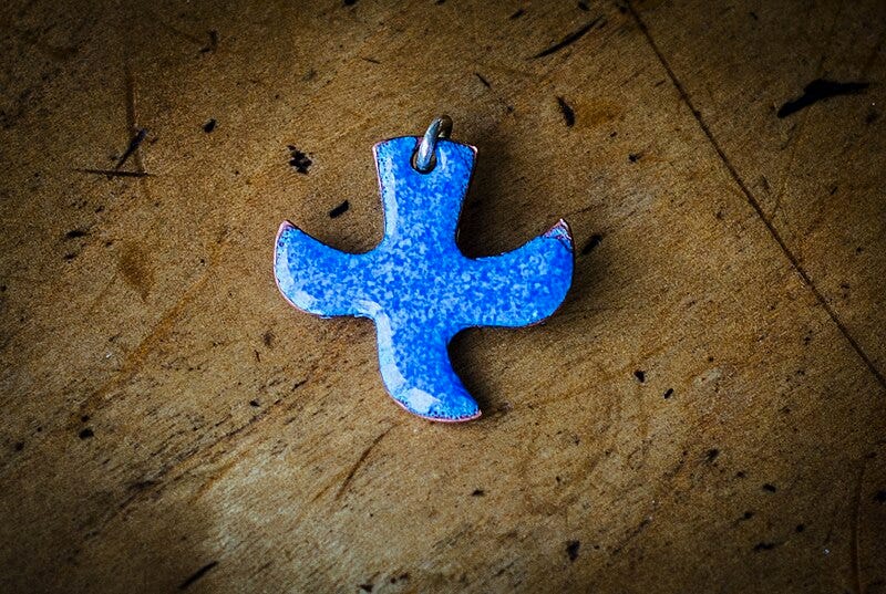 A blue cross shaped pendant

AI-generated content may be incorrect.