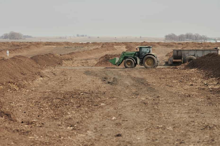A green tractor in a field of dirt piles A green tractor in a field of dirt piles