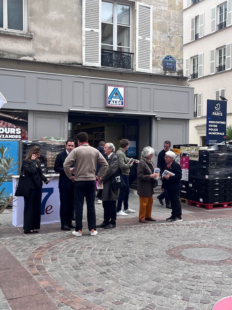 A group of people standing outside a store

AI-generated content may be incorrect.