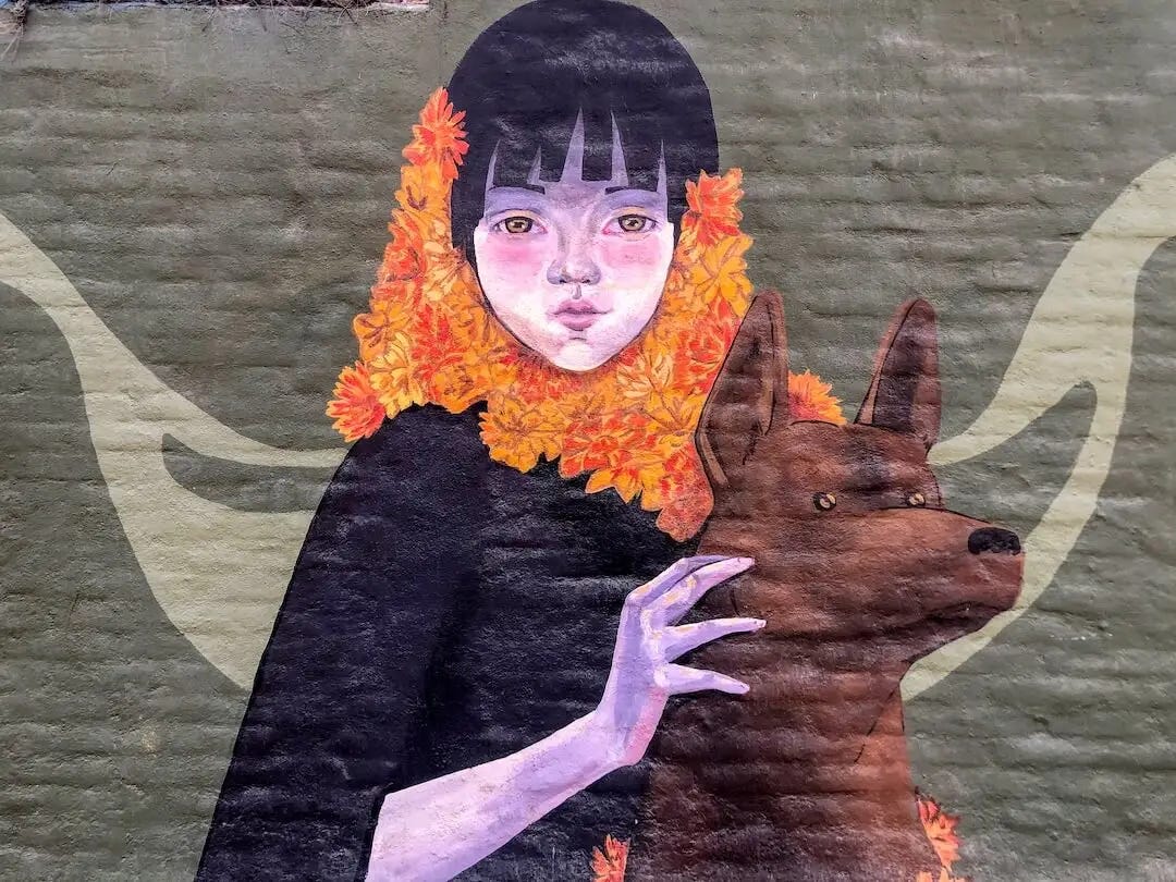 Street art - a girl with an orange leaf scarf holding a brown dog