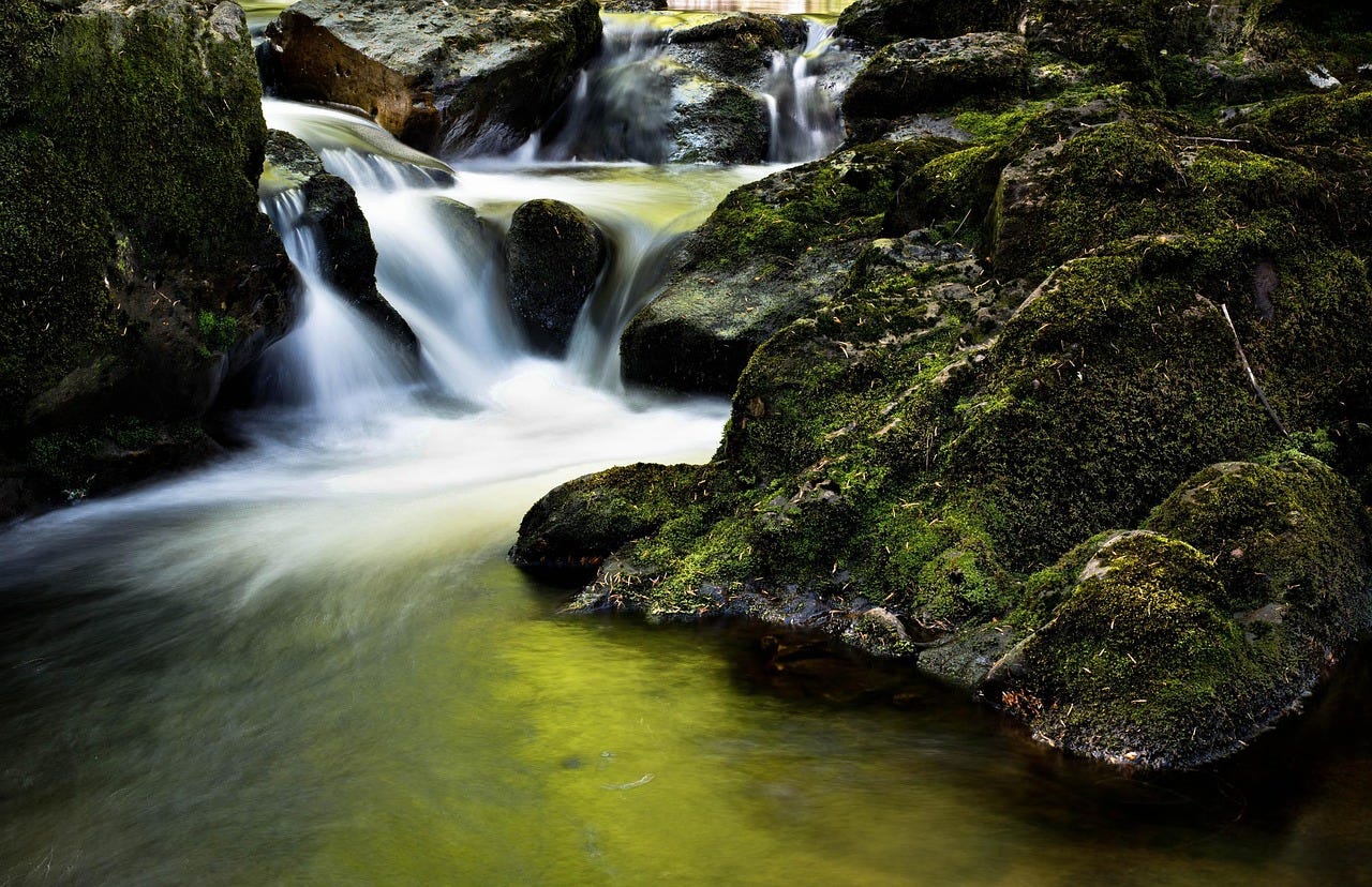 A blurry image of a fast running river over rocks A blurry image of a fast running river over rocks