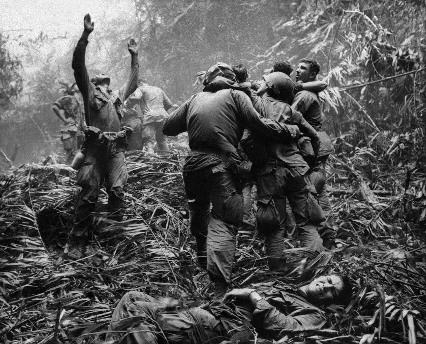 April 1968, near Hue: A 101st Airborne Division first sergeant guides a medevac helicopter through dense jungle to evacuate casualties from a five-day patrol, as fellow troopers aid the wounded. April 1968, near Hue: A 101st Airborne Division first sergeant guides a medevac helicopter through dense jungle to evacuate casualties from a five-day patrol, as fellow troopers aid the wounded.