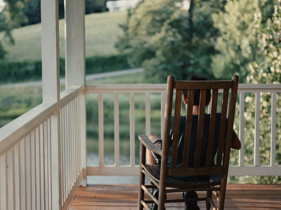 a person sitting on a rocking chair on a porch a person sitting on a rocking chair on a porch