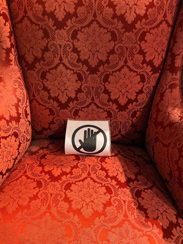 1) A forest of trees coated in ice after freezing rain at dawn. 2) Small red & white clay figurines of buildings, homes, and furniture. 3) A laminated printout of a hand with a cancel sign through it, sitting on the seat of a red & orange floral fabric chair. 4) Wooden double doors with ornate iron grating over stippled glass windows.