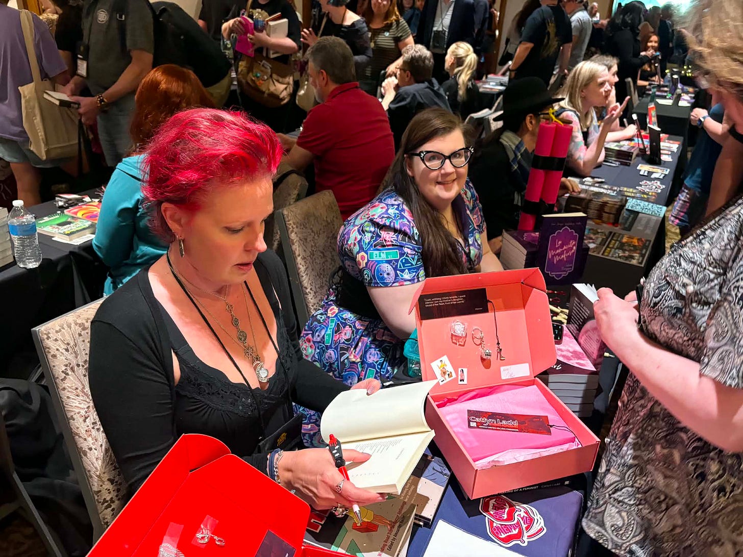 woman with bright red hair signs a book for a fan