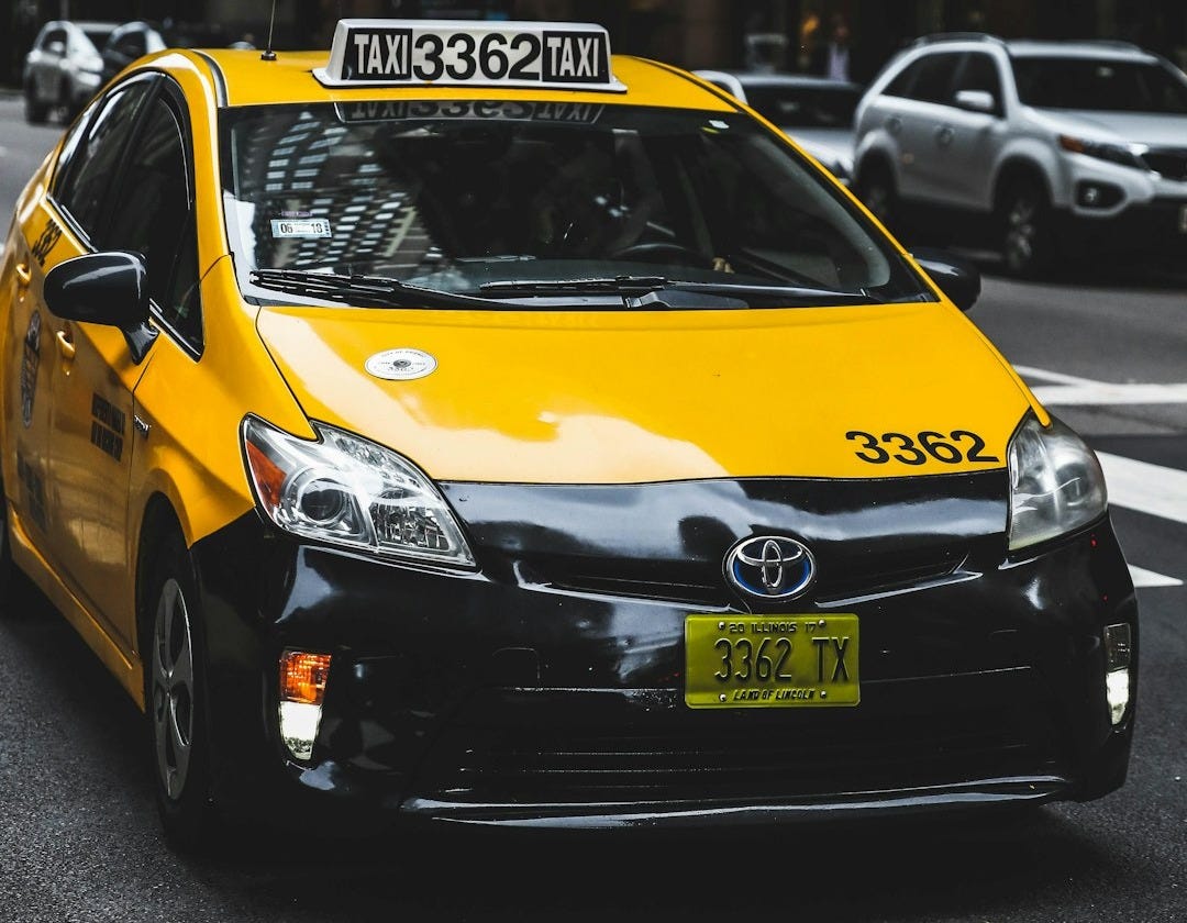Toyota taxicab at the road in the city during day Toyota taxicab at the road in the city during day