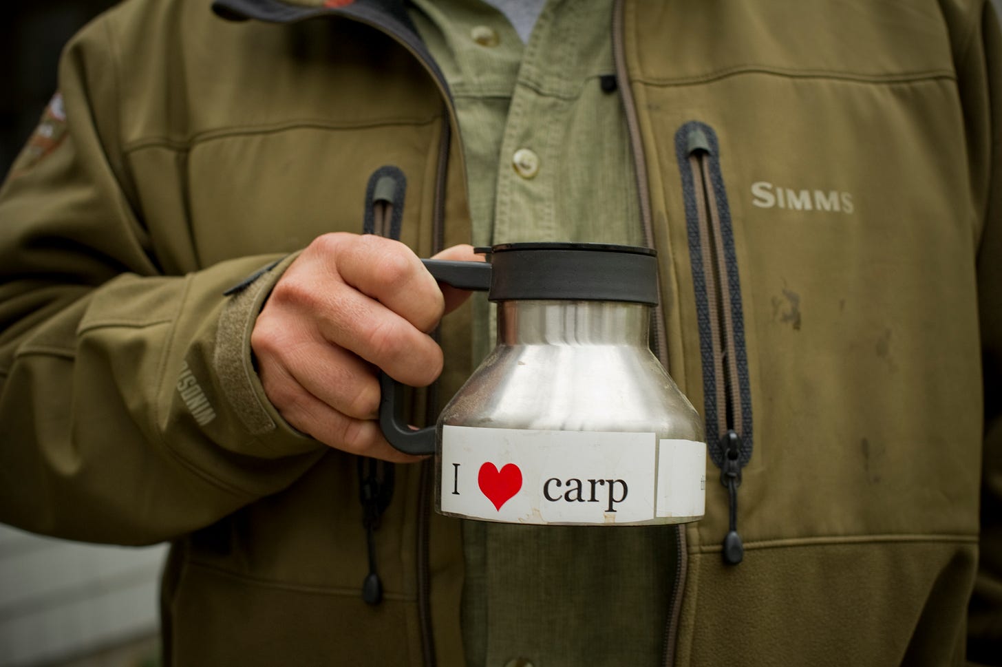 Fishing guide holing a coffee mug that reads: "I love carp."