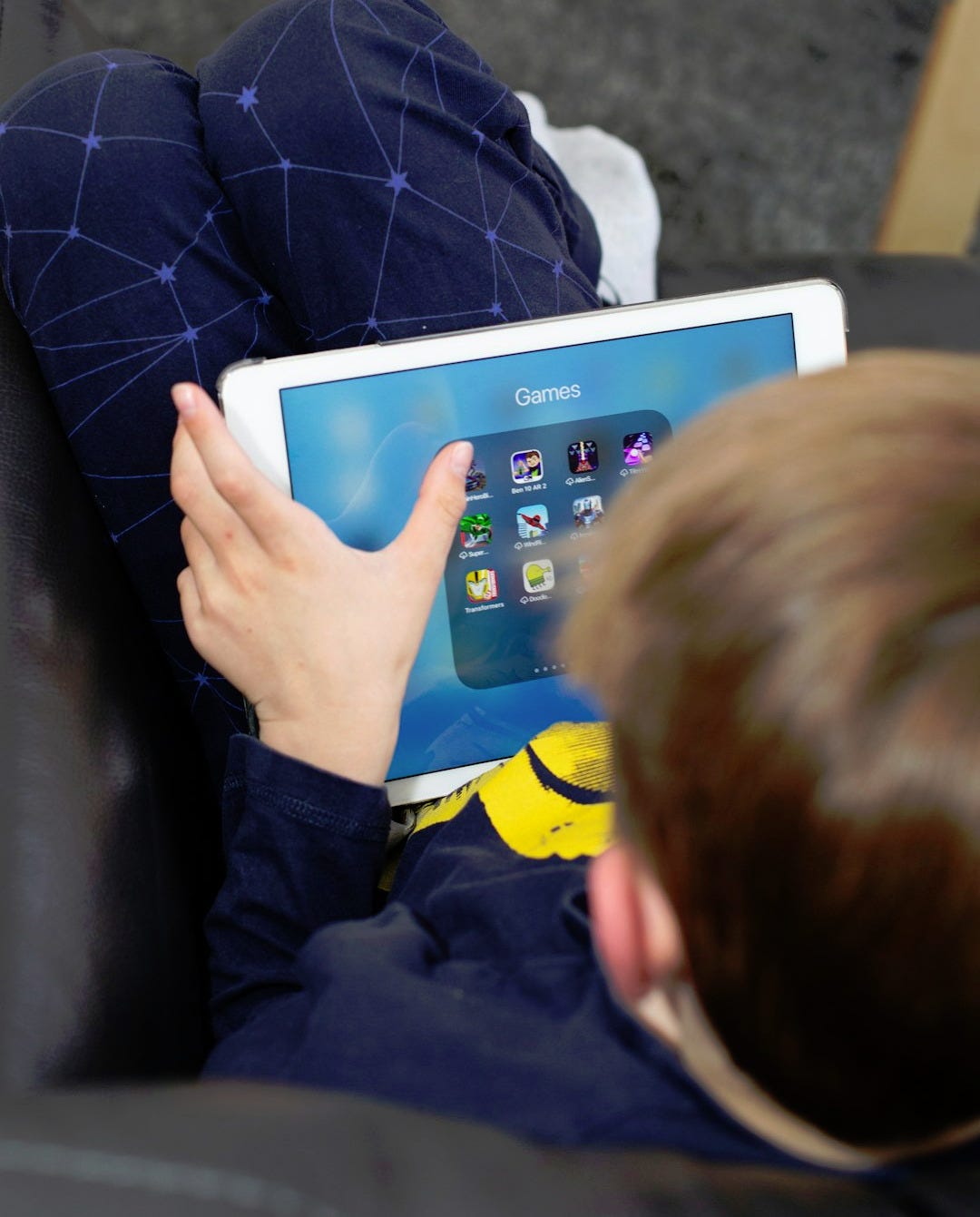 a young boy sitting on a couch holding a tablet a young boy sitting on a couch holding a tablet