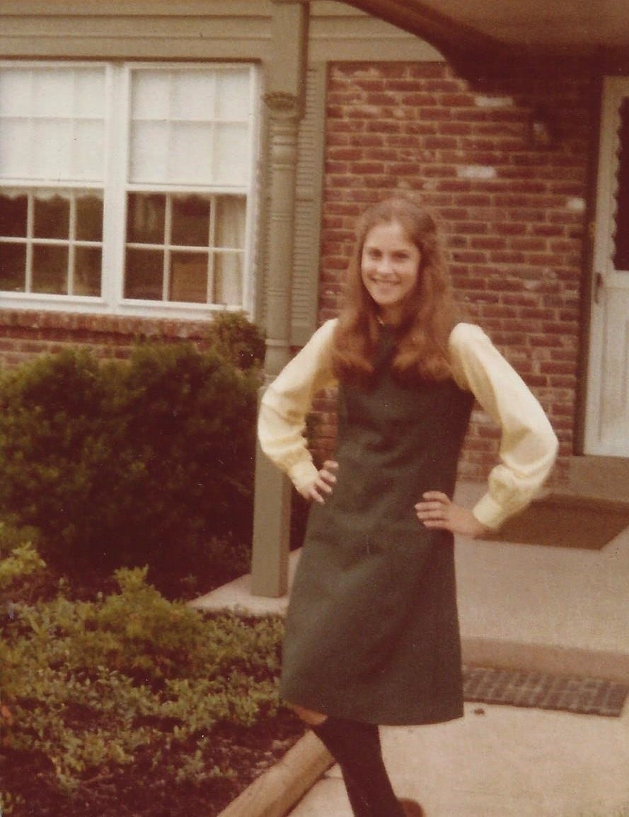 A color photo from the 1980s shows a 14-year-old girl dressed in a Catholic school jumper stands with her hands on her hips outside a suburban colonial on the first day of school