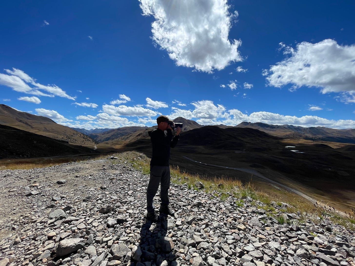 Man with camera standing on top of a mountain with 360 degree views