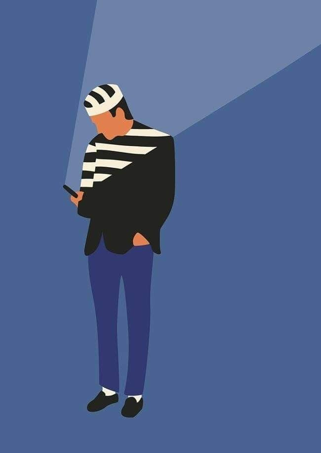 This may contain: a man standing in front of a blue background holding a cell phone and wearing a striped hat