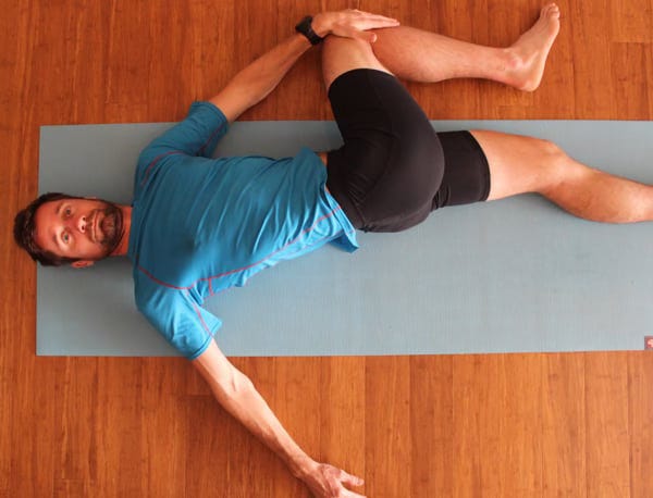 A man performing a supine rotation stretch
