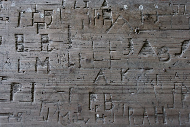 initials carved into the wood of an old church pew