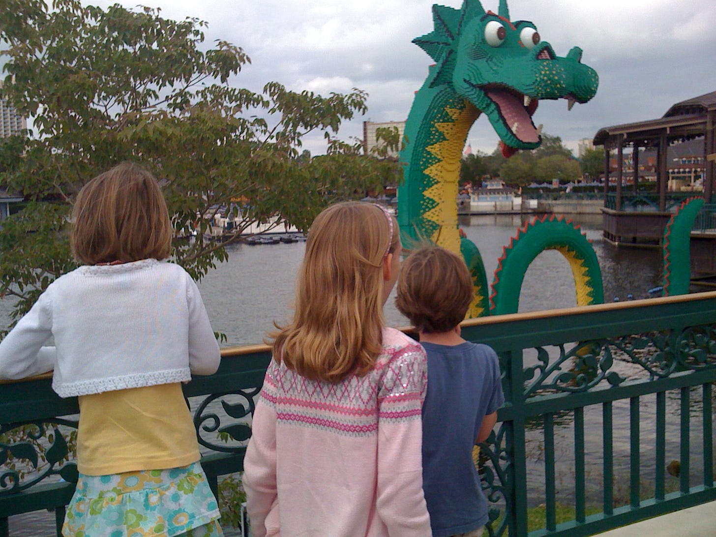three children looking at a dragon made out of Lego at Disney Springs