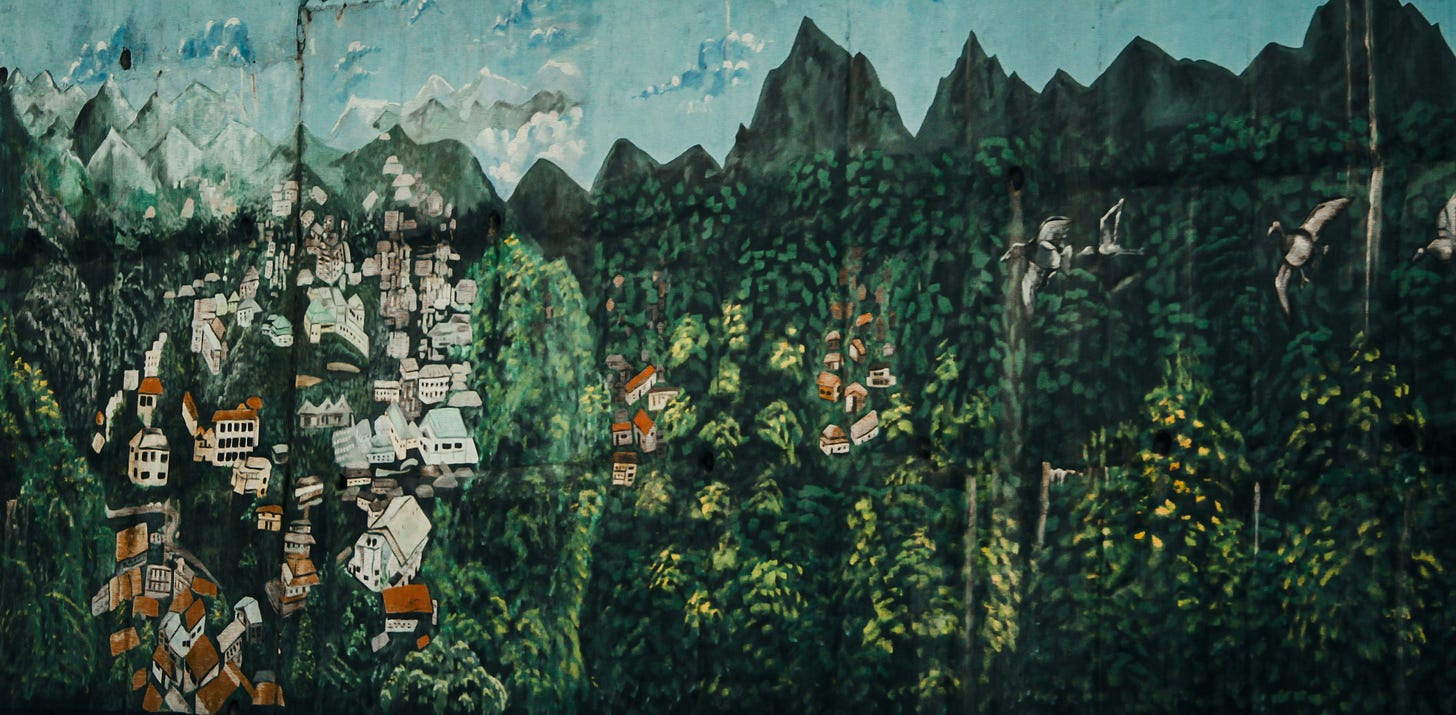 Mural of a landscape with a crowded town surrounded by lush greenery and jagged peaks