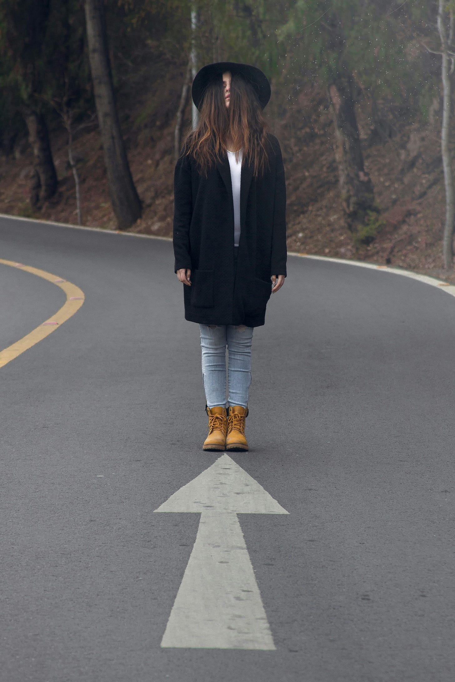 A woman stands on a road with a large arrow painted on the ground pointing toward her, symbolizing the idea that the path isn’t always about moving forward — it’s also about being present in the moment, embracing change, and staying open to new possibilities as they unfold. A woman stands on a road with a large arrow painted on the ground pointing toward her, symbolizing the idea that the path isn’t always about moving forward — it’s also about being present in the moment, embracing change, and staying open to new possibilities as they unfold.