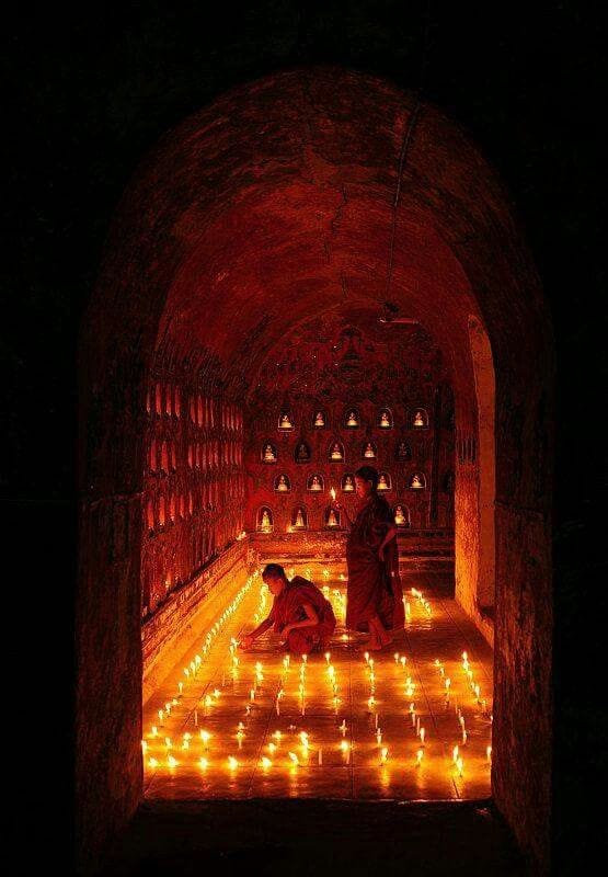 This may contain: two people sitting on the ground in a tunnel with candles lit up all around them