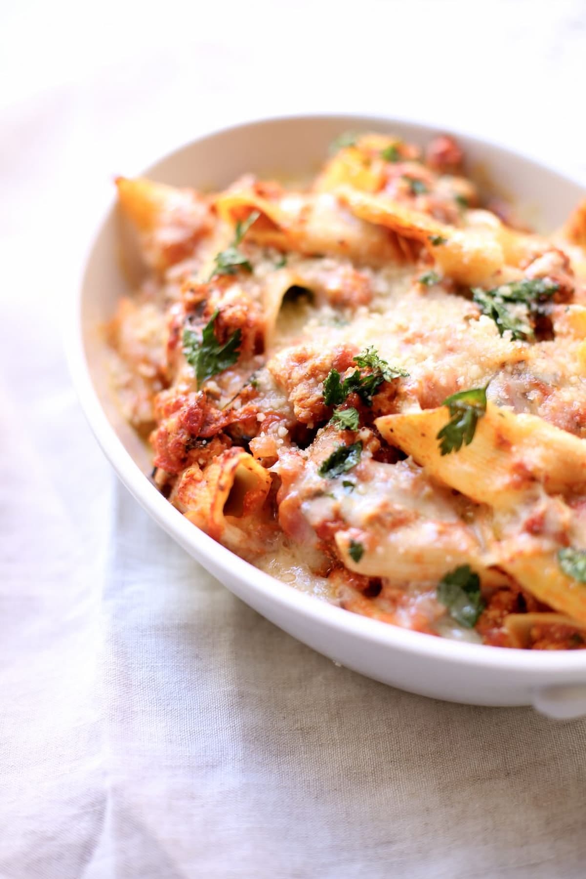 A white casserole dish of baked pasta with chicken sausage 
