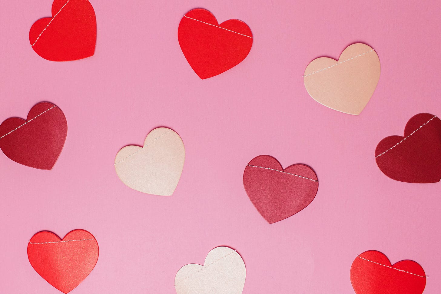 Paper hearts on a pale pink background.
