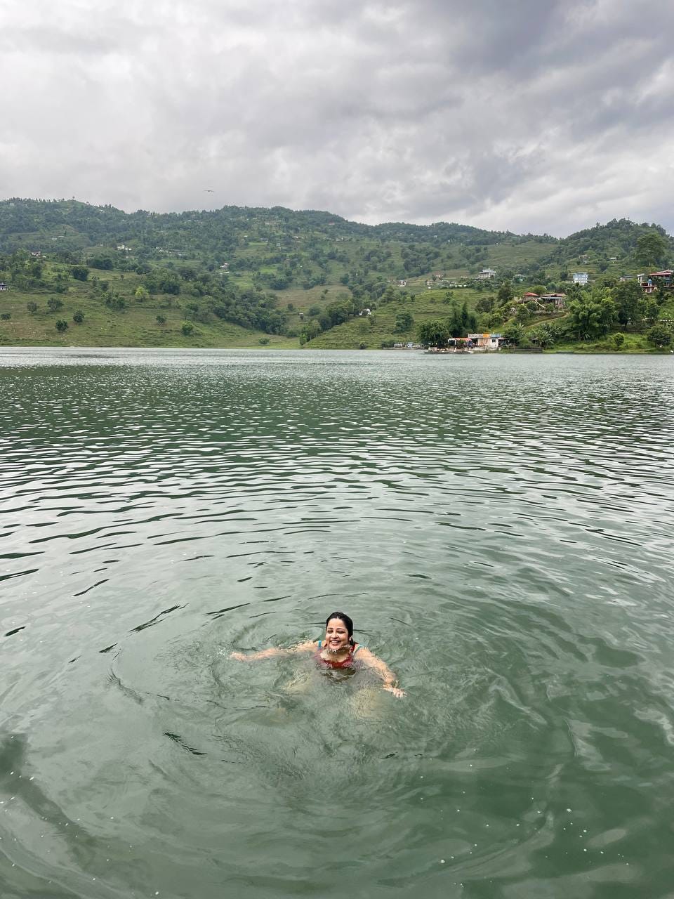My head is bobbing in a lake and you can see the hills behind. I look tiny against the size of the lake and the hills.