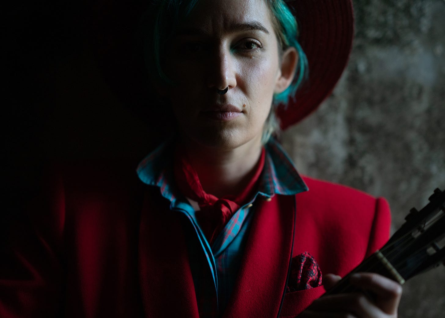 A person holding a guitar and looking into the camera