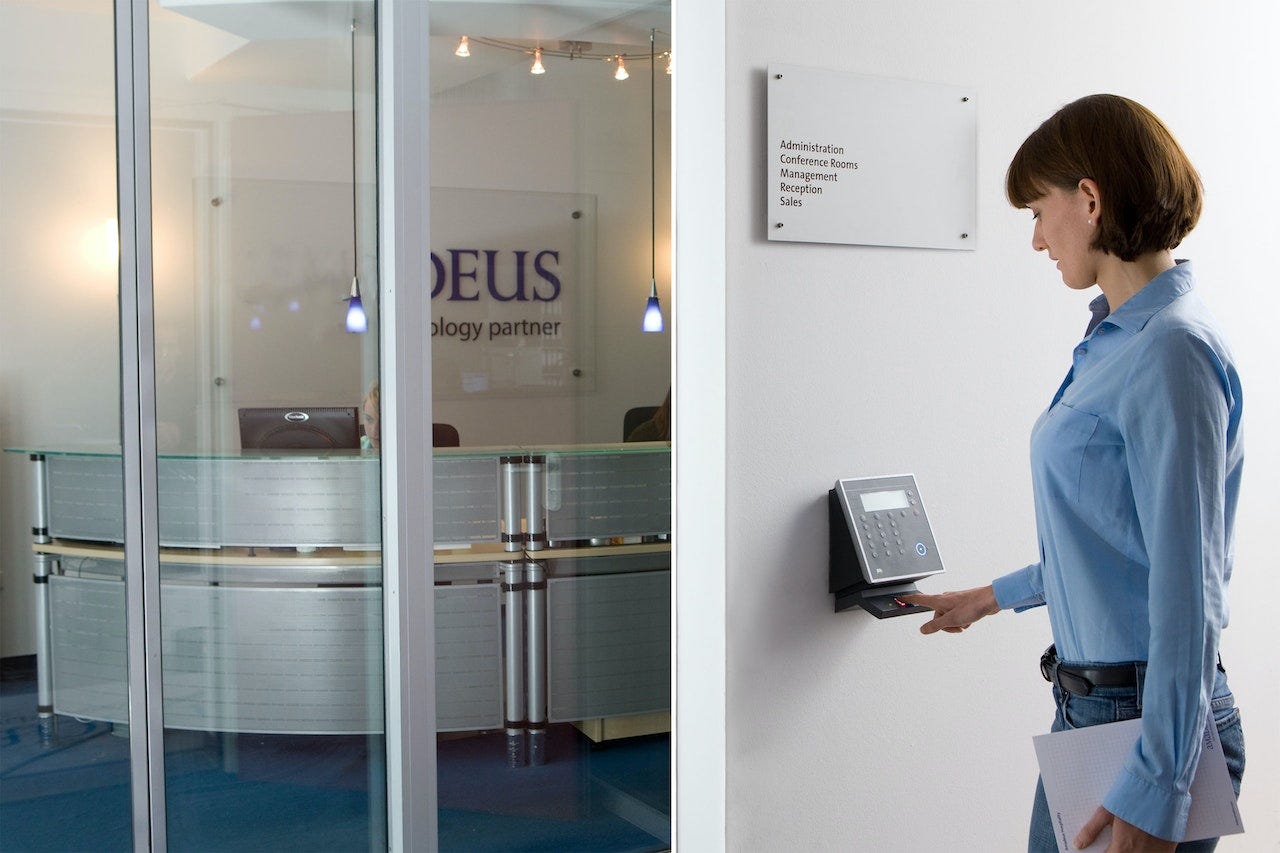 A photo of a woman scanning her fingerprint to enter an office A photo of a woman scanning her fingerprint to enter an office