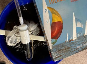 bucket of worm tea brewing with a text book on top