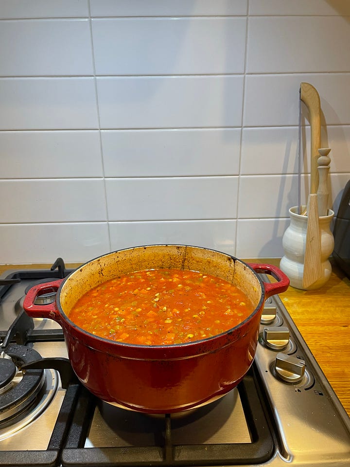 Dutch oven filled with lentil bolognese on the stove. A bowl of lentil bolognese with spaghetti topped with basil and parmesan on a dinner table.