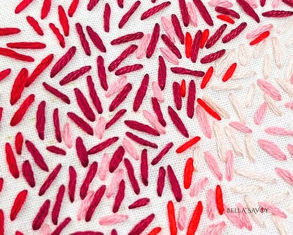 red, pink, and white seed stitches placed randomly on white fabric