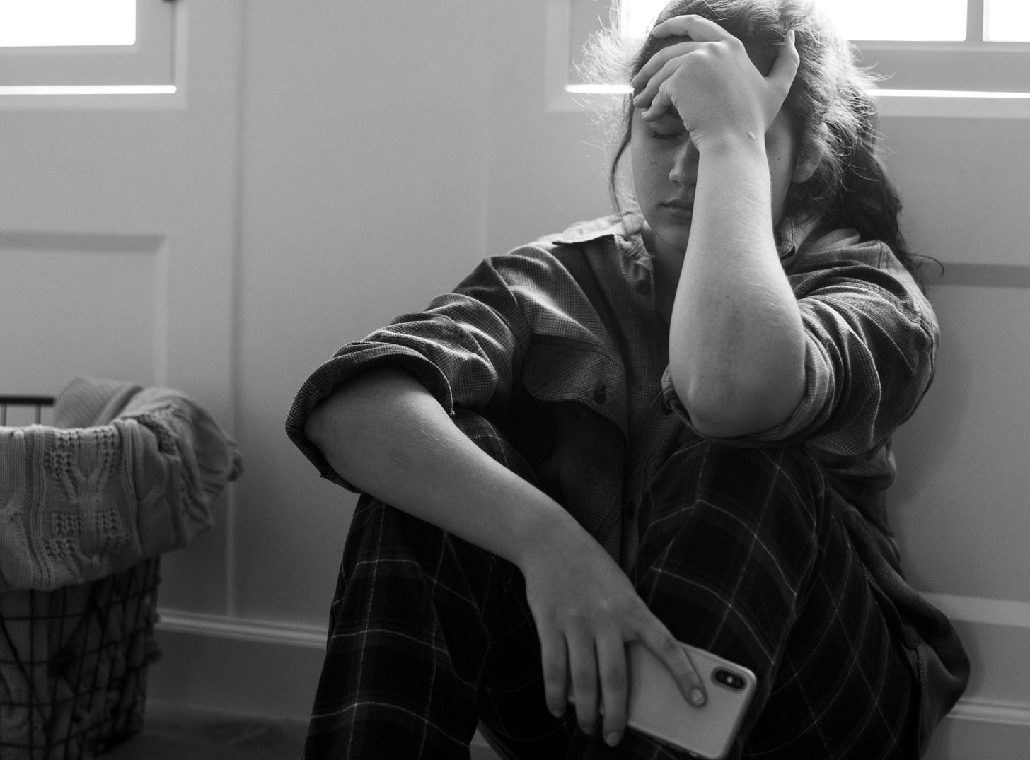 Picture of teen sitting, holding cell phone, in anguish