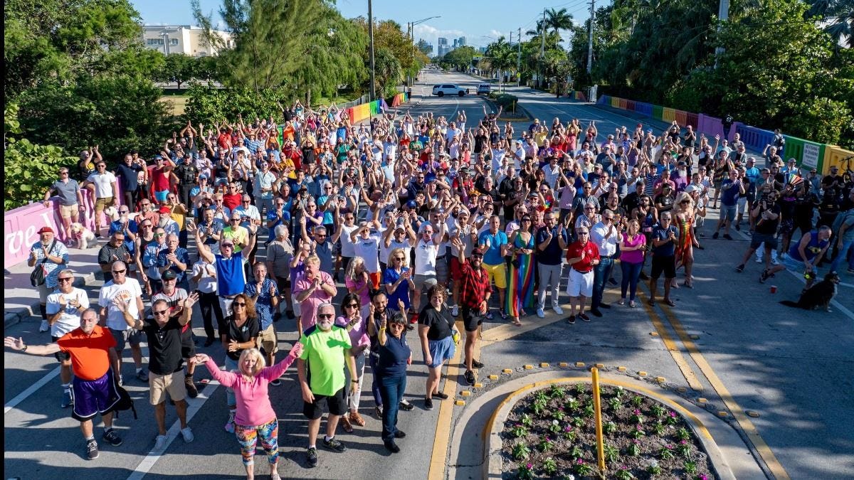 A large group of people gathered on the Wilton Manor rainbow bridge, celebrating together.