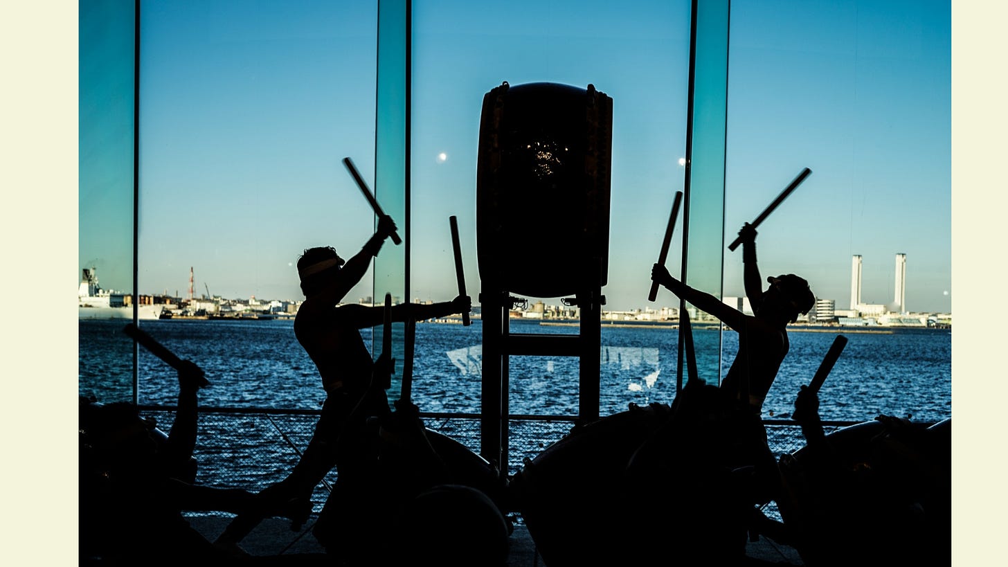 Silhouettes of people beating large drums Silhouettes of people beating large drums