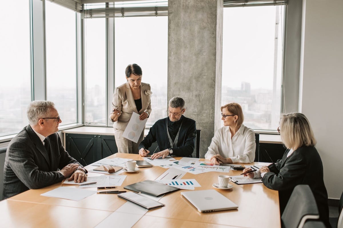 A senior executive facilitating an intimate strategic meeting with business partners, representing relationship-driven B2B demand generation. A senior executive facilitating an intimate strategic meeting with business partners, representing relationship-driven B2B demand generation.