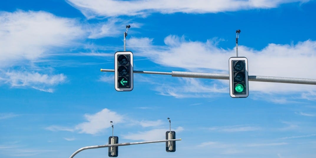 Traffic lights are green against a blue sky.