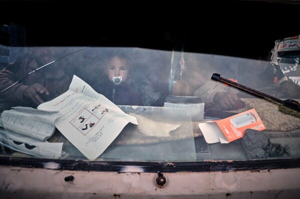 A young child looks through a truck's windshield as displaced families prepare to leave al-Talayi camp in Hassakeh, Syria, Tuesday, Oct. 13, 2026. Around 450 families are returning to the Ras al-Ayn countryside, seven years after a Turkish military offensive forced them to flee. (AP Photo/Baderkhan Ahmad)