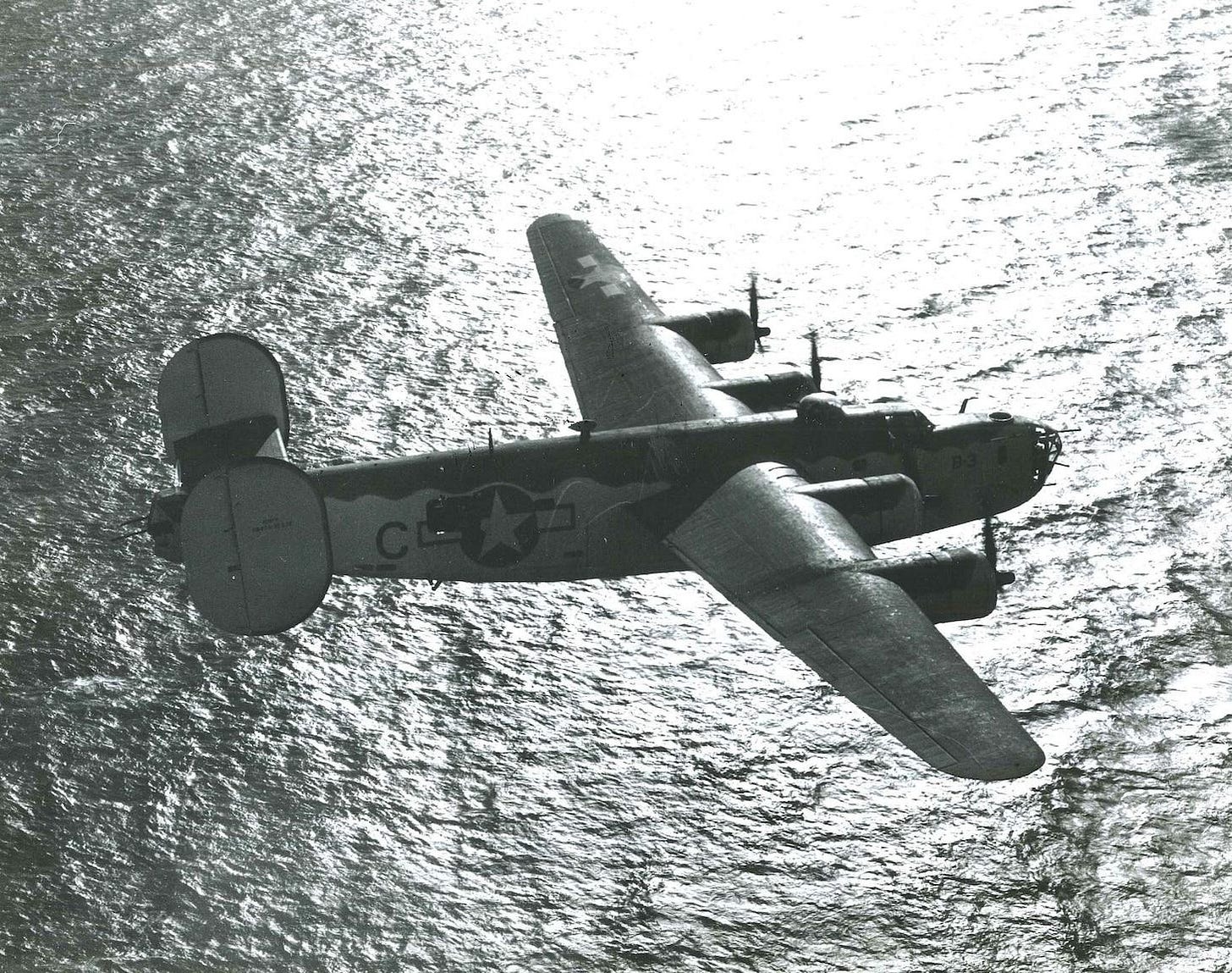The crisp, clear black- and white-photograph of a PB4Y-1 “Liberator” airplane viewed from its starboard side, flying over the Bay of Biscay in November 1943
