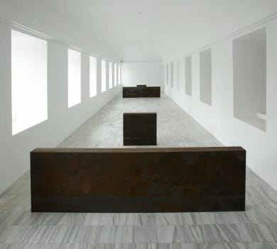 a large white room with two metal sculptures at either end a large white room with two metal sculptures at either end
