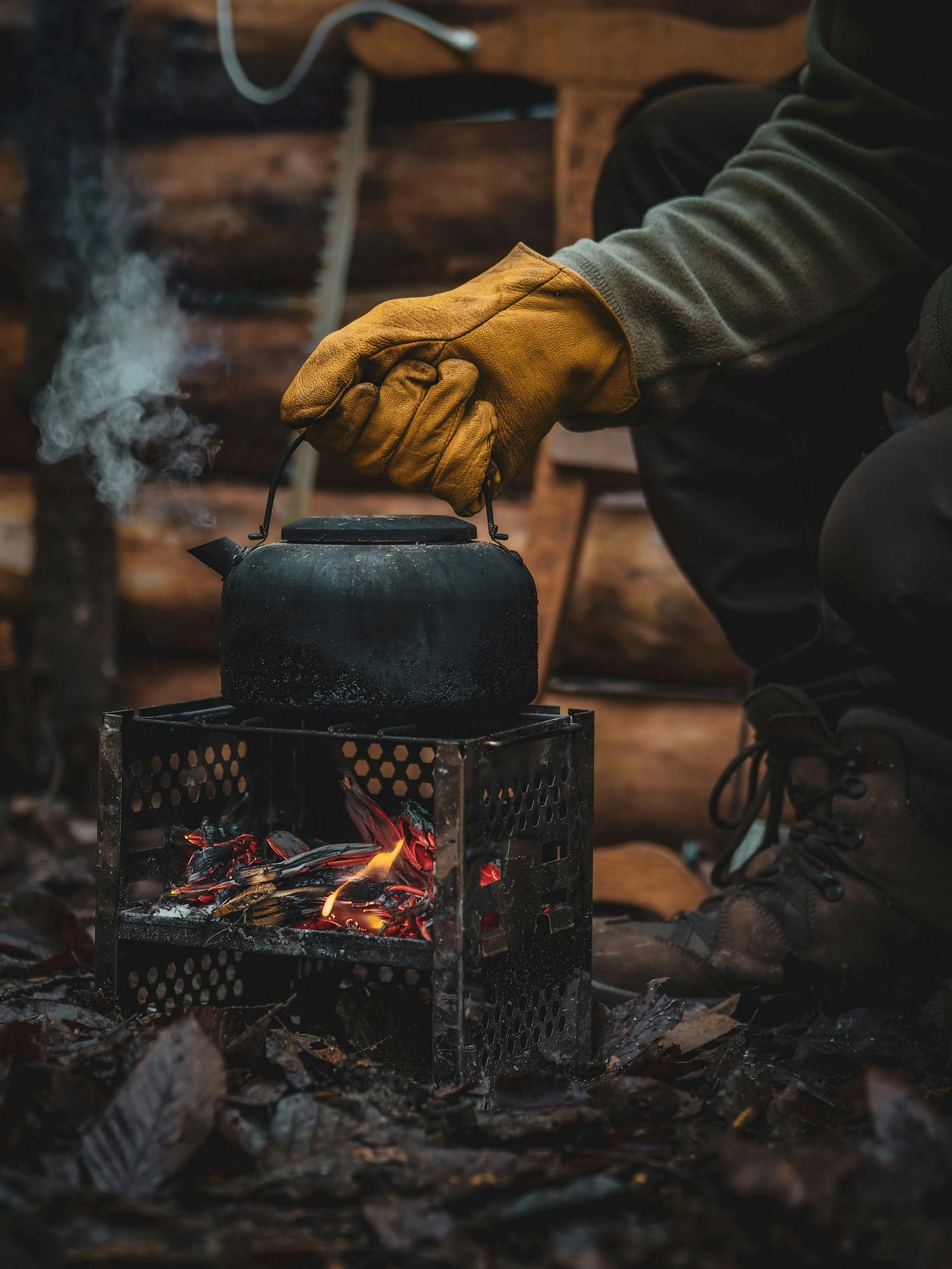 Free Close-up of a kettle on a camping stove with glove-covered hand adjusting it outdoors. Stock Photo